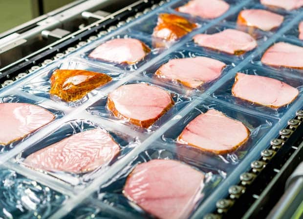 Slices of meat being vacuum-sealed in plastic packaging